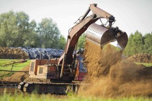 Excavadora trabajando en la remediación y valorización de suelos, parte de las soluciones de gestión medioambiental y de residuos sostenibles.